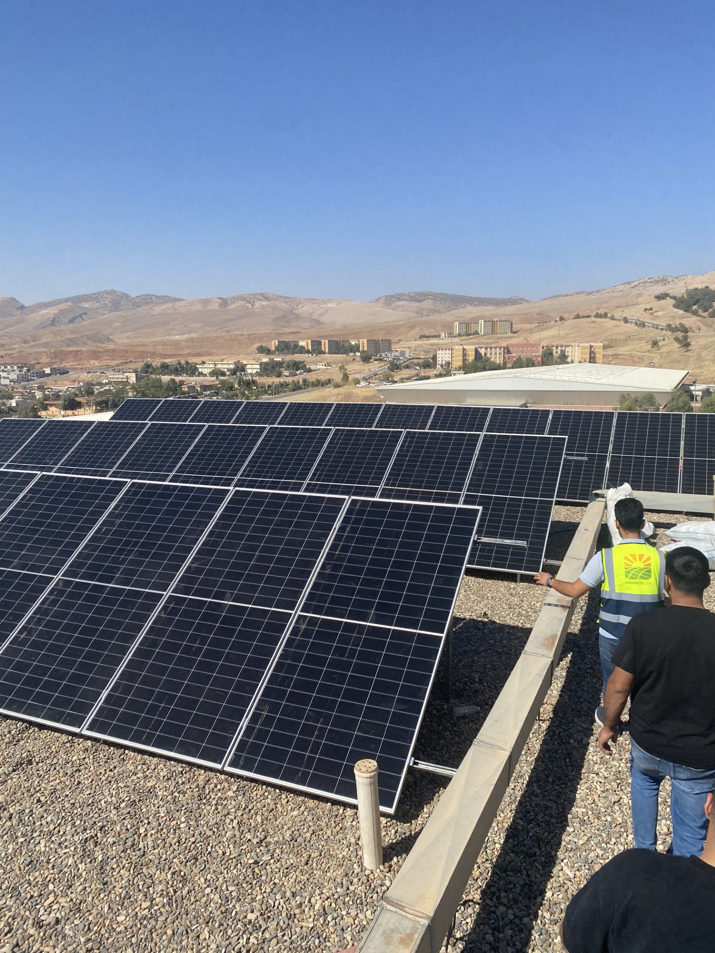 Progress Sun team with rooftop solar panels at Koya University