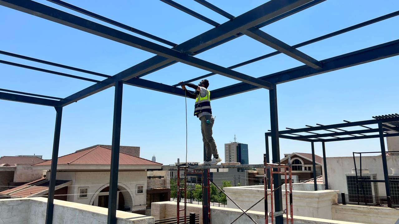 Worker installing the engineered steel substructure for an elevated rooftop solar canopy